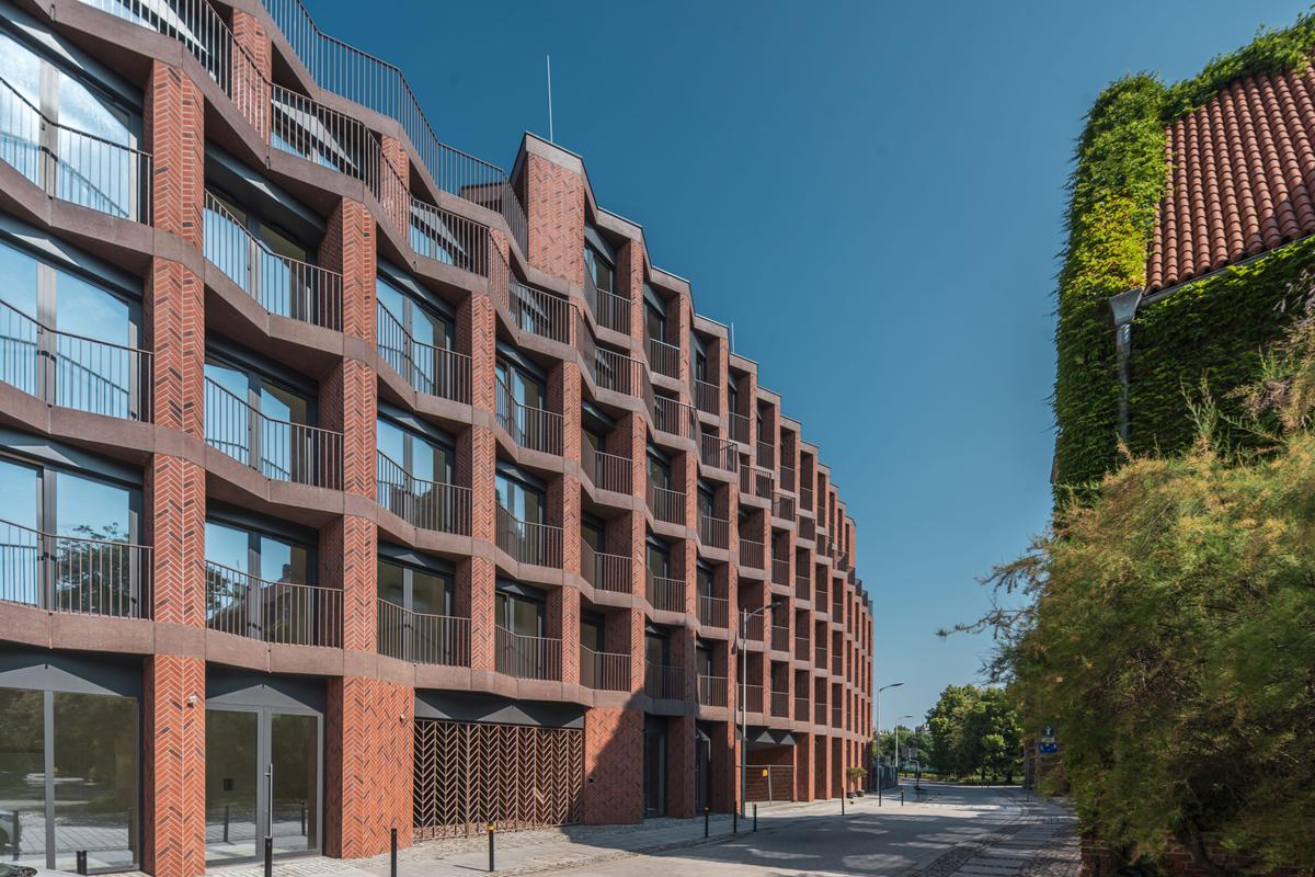 Elewacja apartamentowca wykonana z czerwonej cegły i prefabrykatów betonowych barwionych w masie